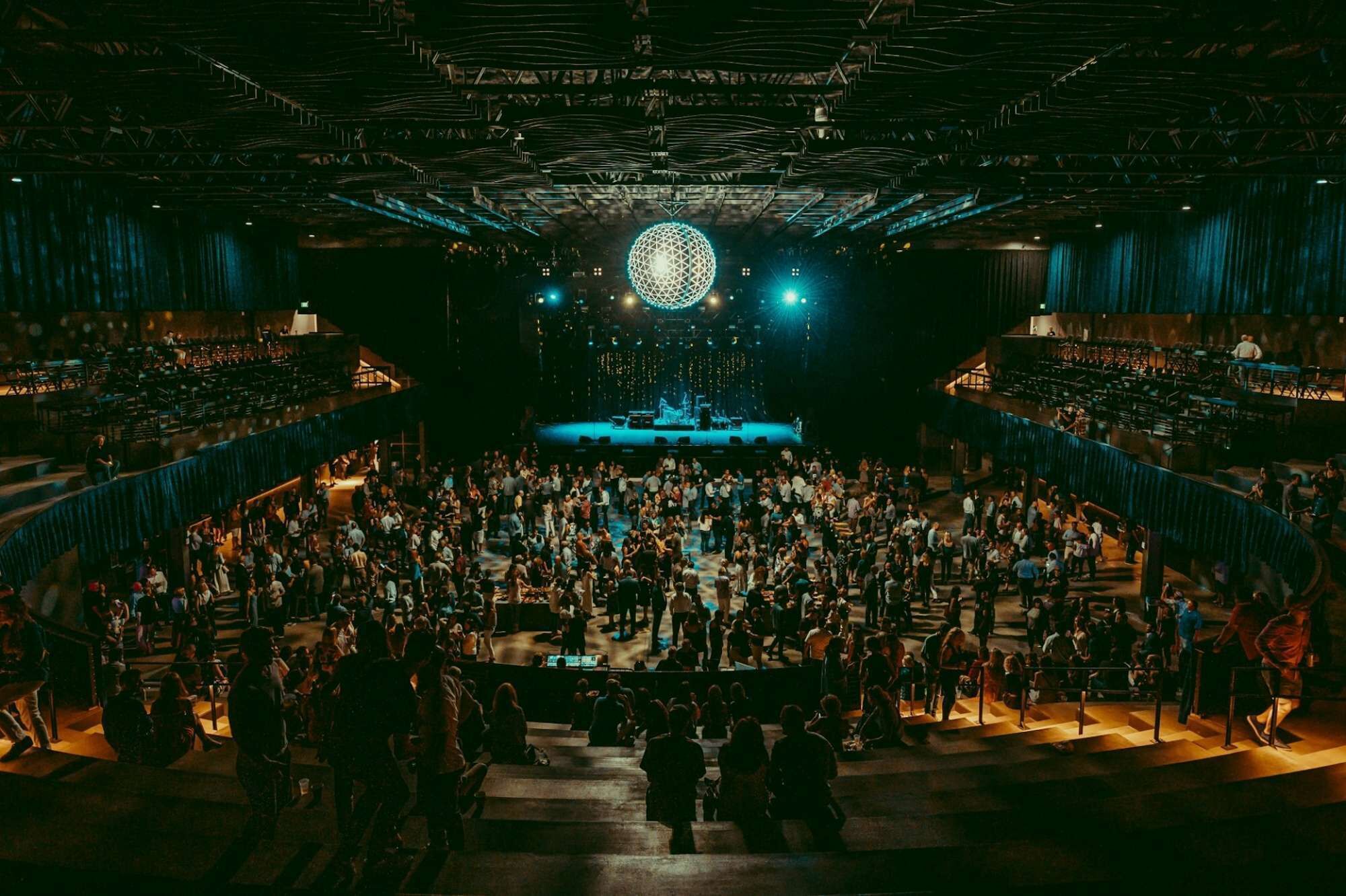 Um espaço amplo e coberto com vários níveis de assentos e um palco central.