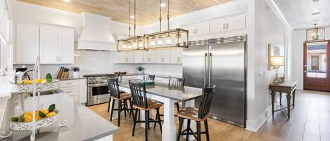 Una cocina moderna con armarios blancos, un refrigerador de acero inoxidable y una isla central con sillas.