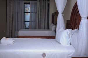A hotel room with two beds, a wooden headboard, and a window with curtains.