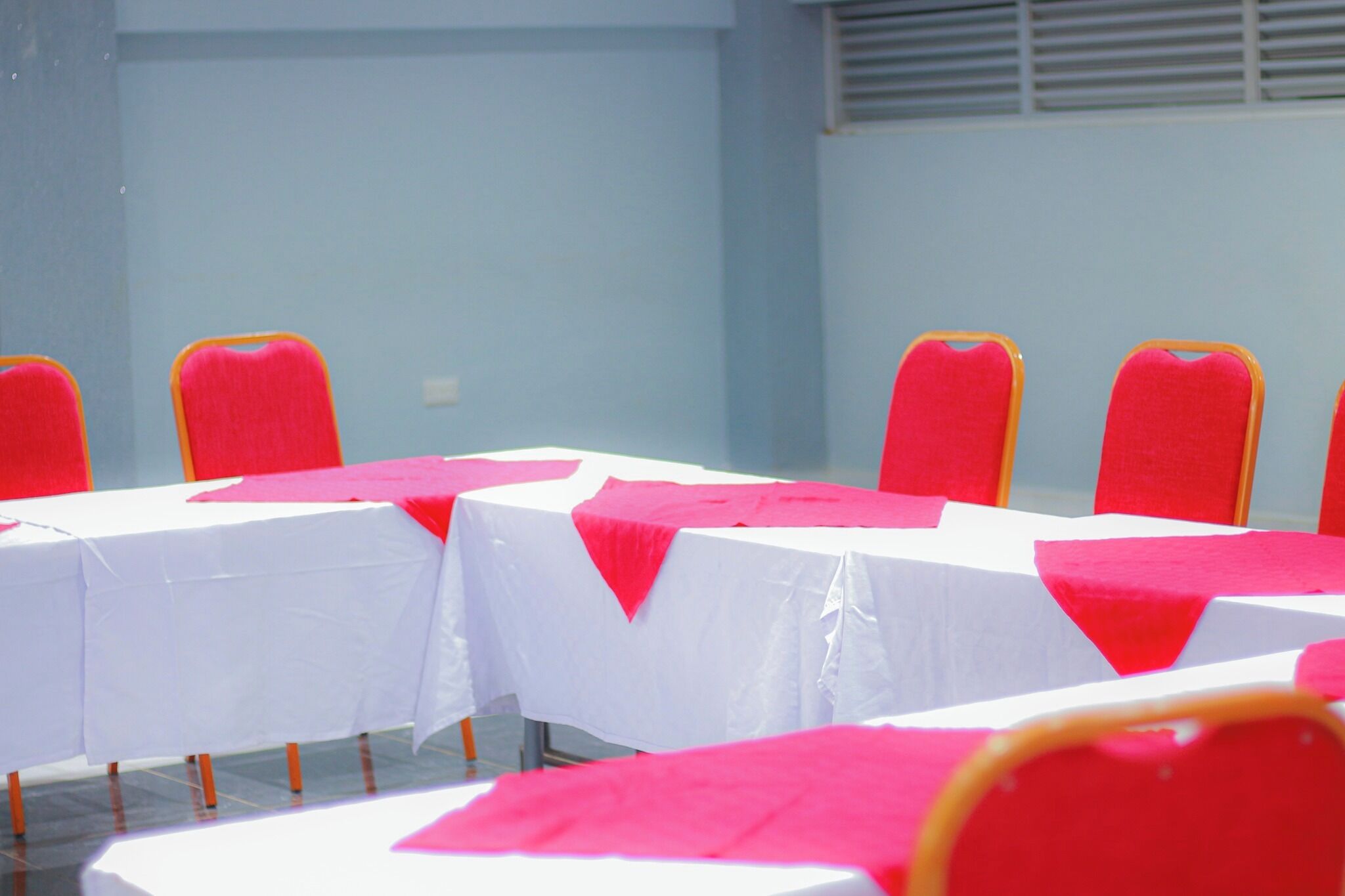 A conference room with white tables and red chairs, arranged in rows.