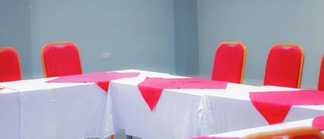 A conference room with white tables and red chairs, arranged in rows.