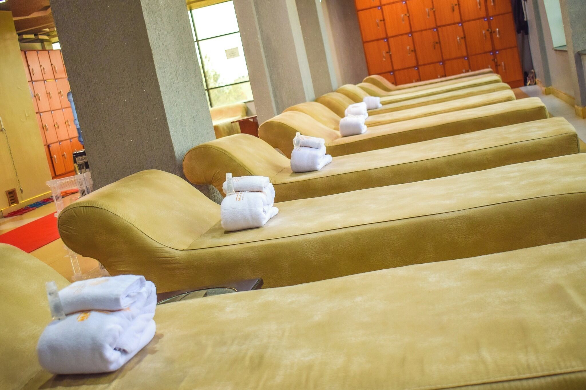 Een rij massage stoelen met handdoeken, een rood tapijt en houten kasten op de achtergrond.
