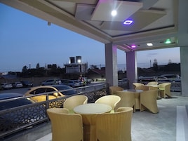 An outdoor seating area with wicker furniture and a view of a parking lot and buildings in the background.