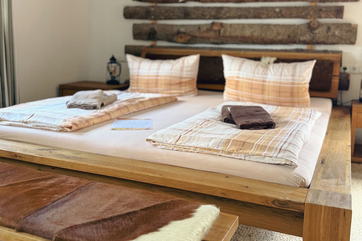 A bed with a wooden headboard, two pillows, a blanket, and a brown rug.
