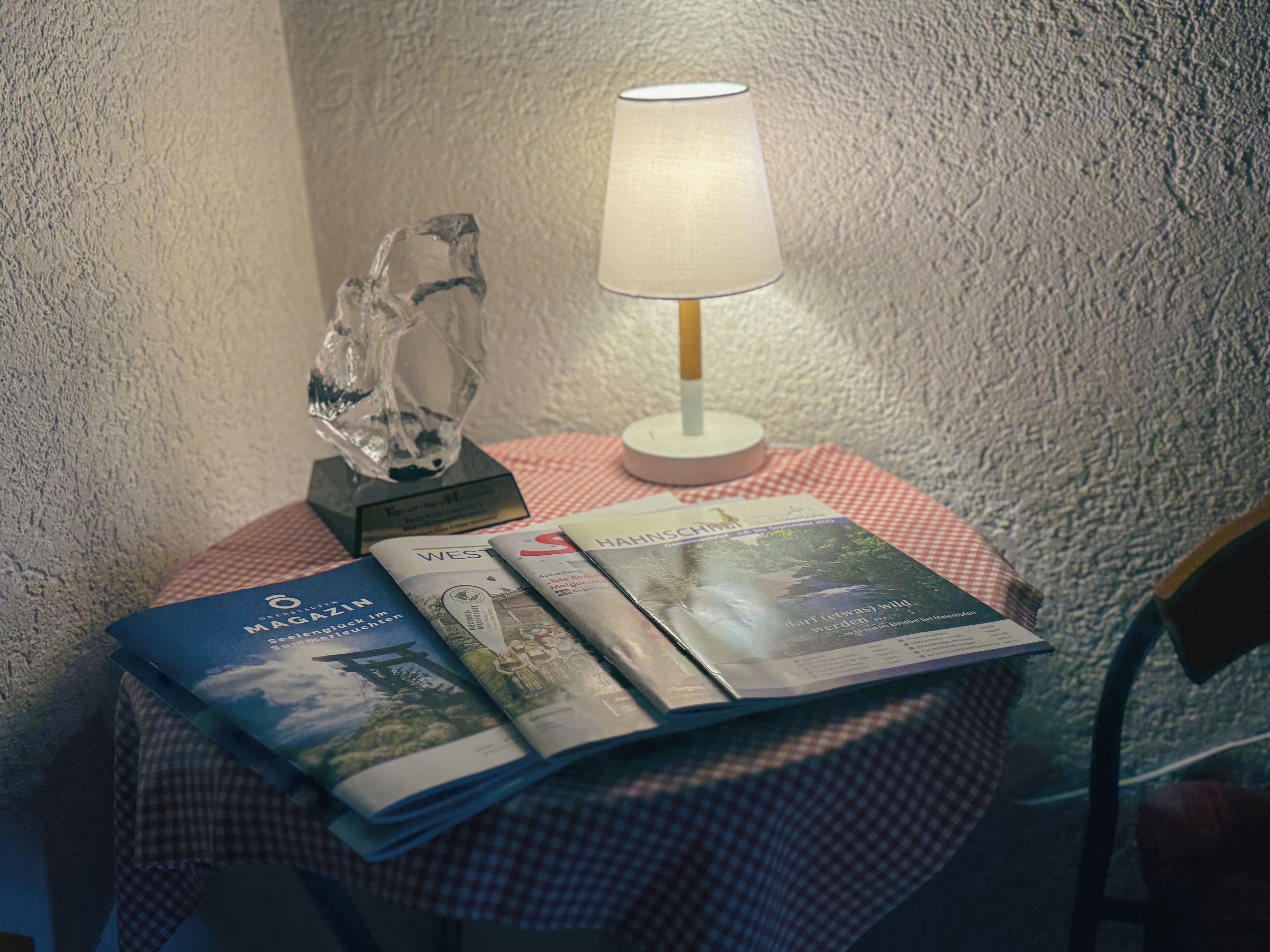 Ein Tisch mit kariertem Tuch, einer Lampe und einigen Zeitschriften.