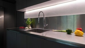 Uma cozinha moderna com uma pia de aço inoxidável, um jardim vertical integrado e vegetais frescos.