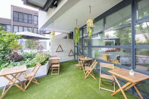 Un espace patio avec des tables et des chaises en bois, des jardinières suspendues et un mur en briques.