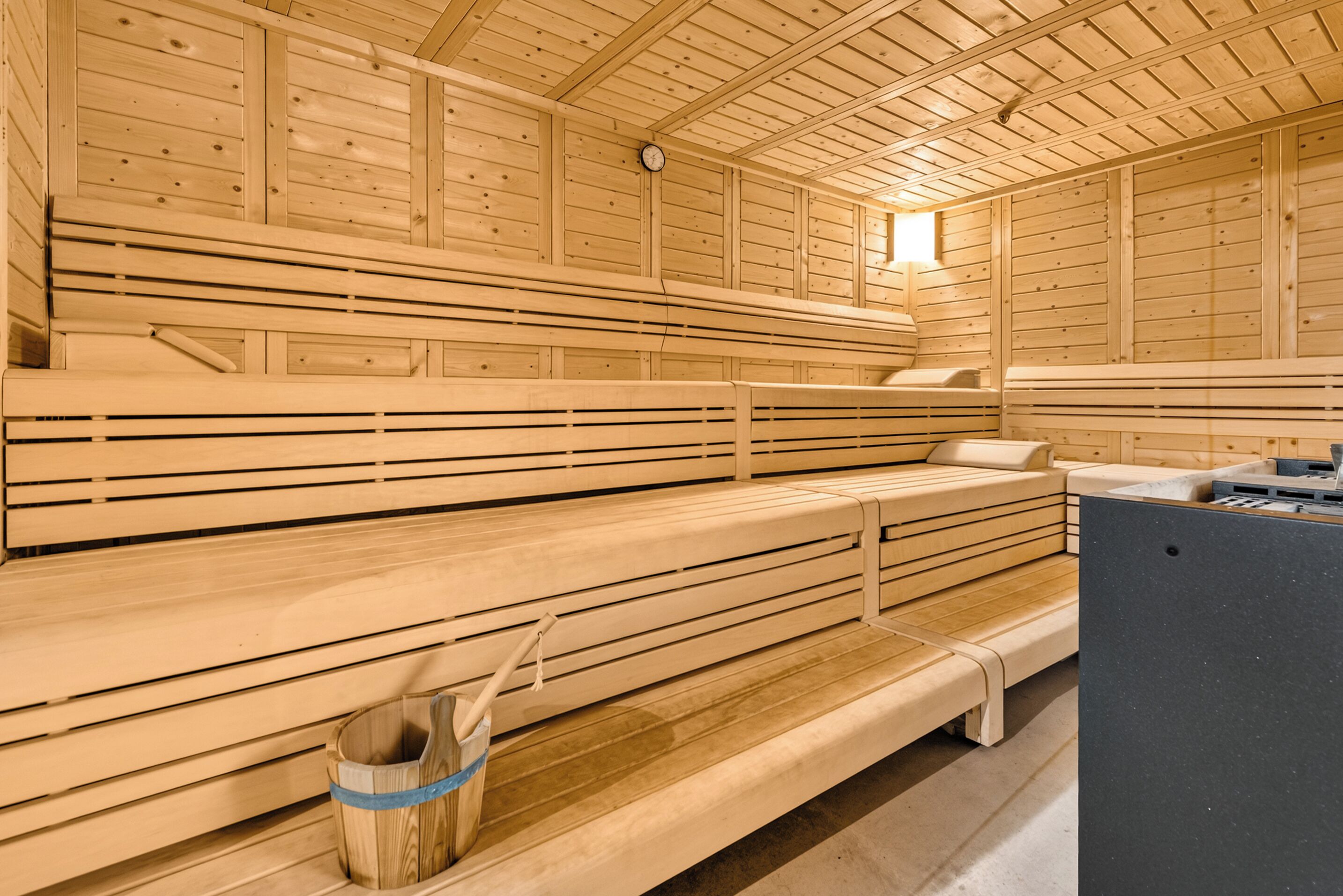 Una sauna amb bancs de fusta, un penjador de tovalloles i un escalfador.