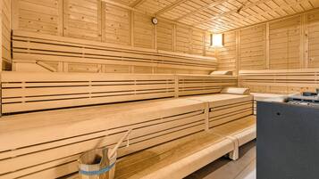 Una sauna amb bancs de fusta, un penjador de tovalloles i un escalfador.