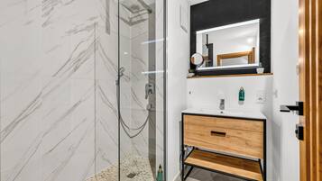 A modern bathroom with a glass-enclosed shower, a wooden vanity, and a large mirror.
