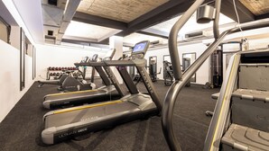 Une salle de sport équipée de tapis de course, d’appareils de musculation et d’un mur recouvert de miroirs.