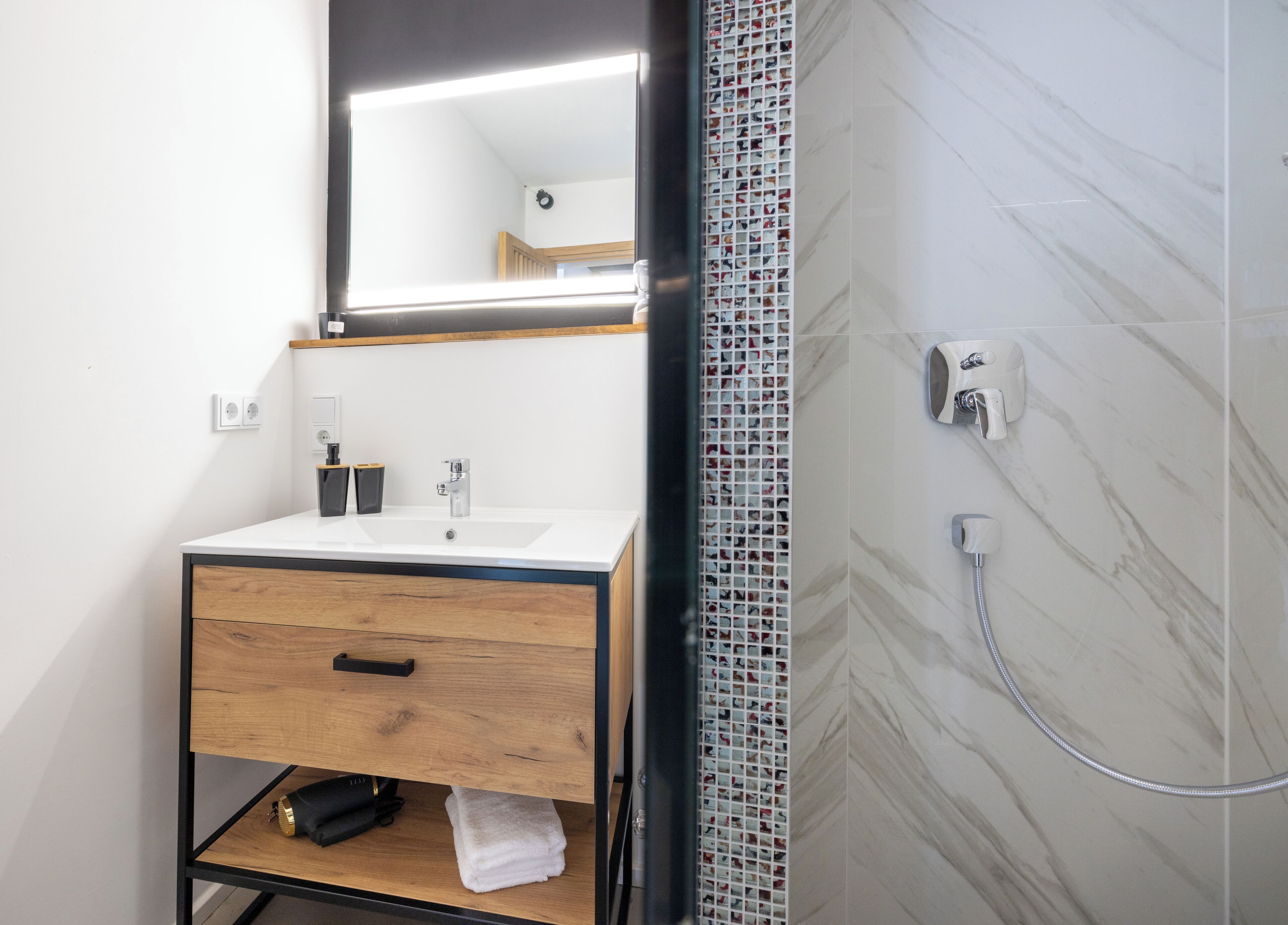 A modern bathroom with a wooden vanity, a mirror, a sink, and a shower.