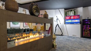 Un hall d’entrée moderne doté d’une cheminée, d’un espace salon et d’un téléviseur diffusant du contenu.