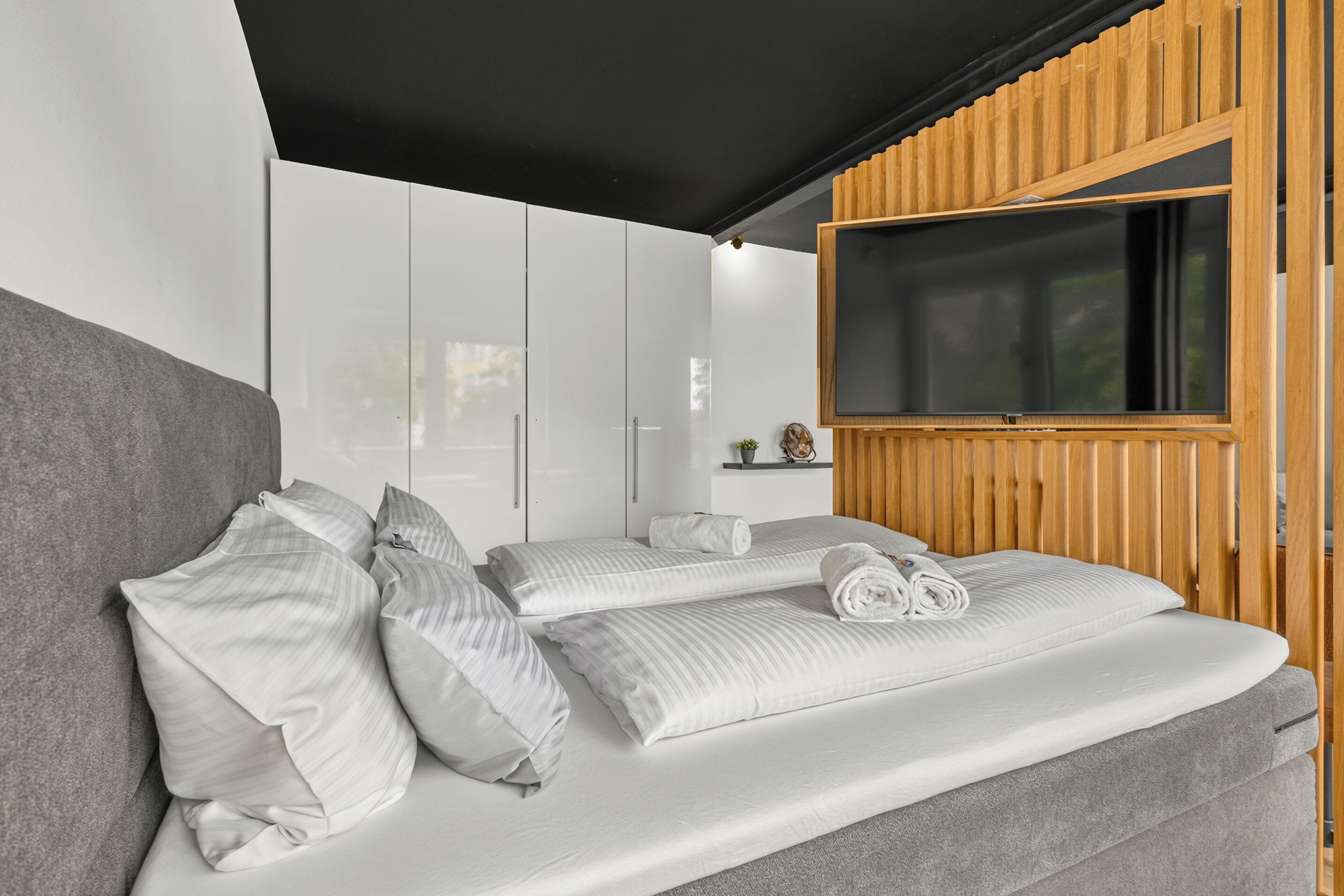 Un dormitorio moderno con una cama grande, armario empotrado y televisor.