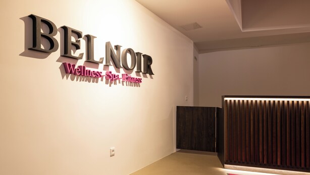 Un intérieur moderne avec une enseigne indiquant : « BEL NOIR, centre de bien-être, spa et salle de sport ».