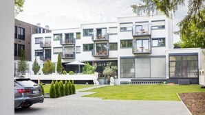 Un immeuble moderne à plusieurs étages, doté de balcons, d’une allée pavée et d’une pelouse bien entretenue.