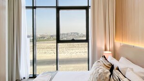 Habitación de hotel con una cama grande, vista a un paisaje desértico y diseño moderno.