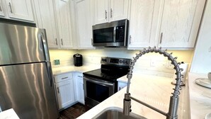 A modern kitchen with stainless steel appliances, white cabinets, and a unique spring-mounted faucet.
