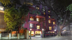 Um edifício com vários andares, varandas e janelas iluminadas, com a placa 