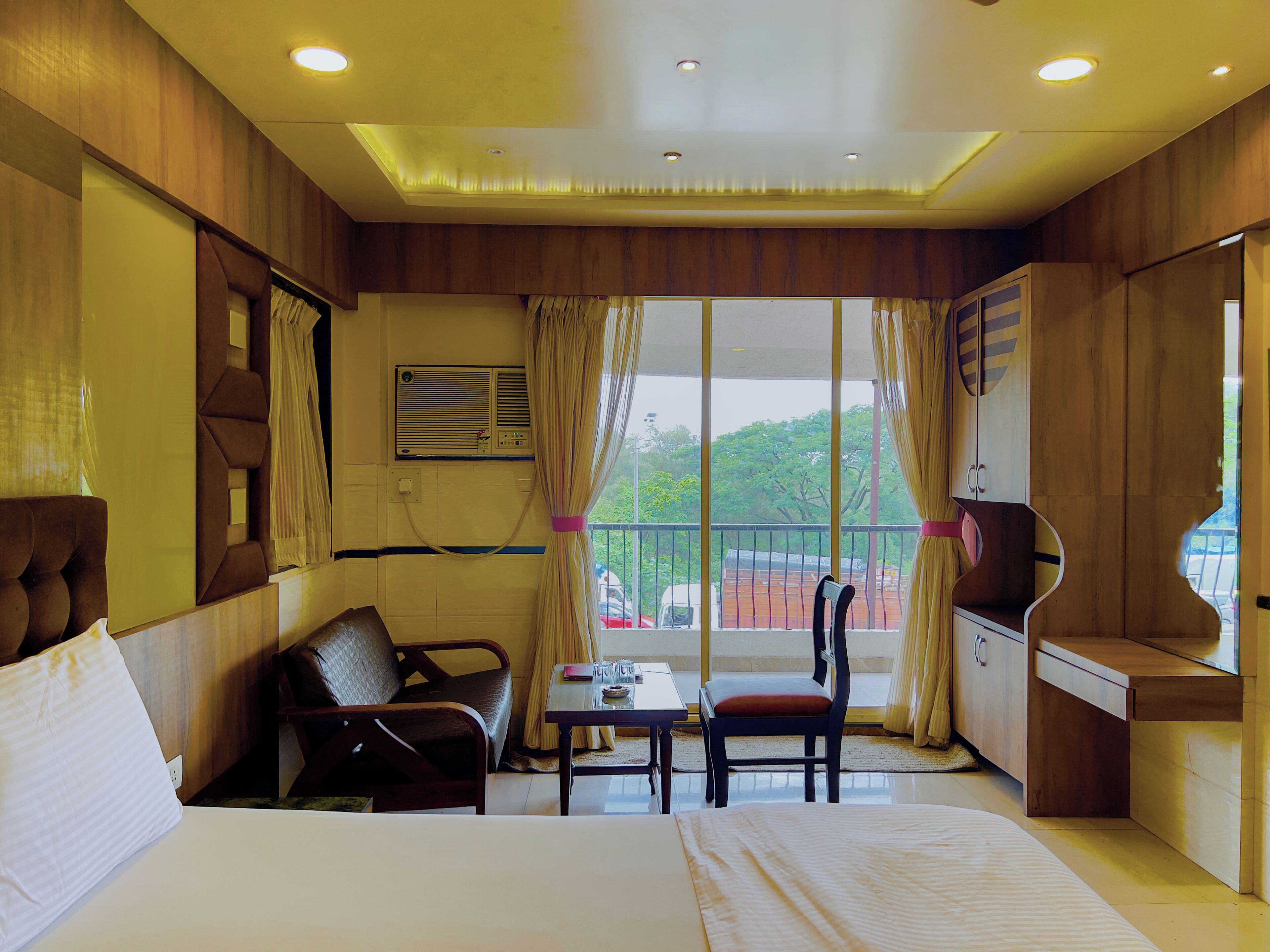 A hotel room with a bed, a desk, a chair, and a window with curtains.