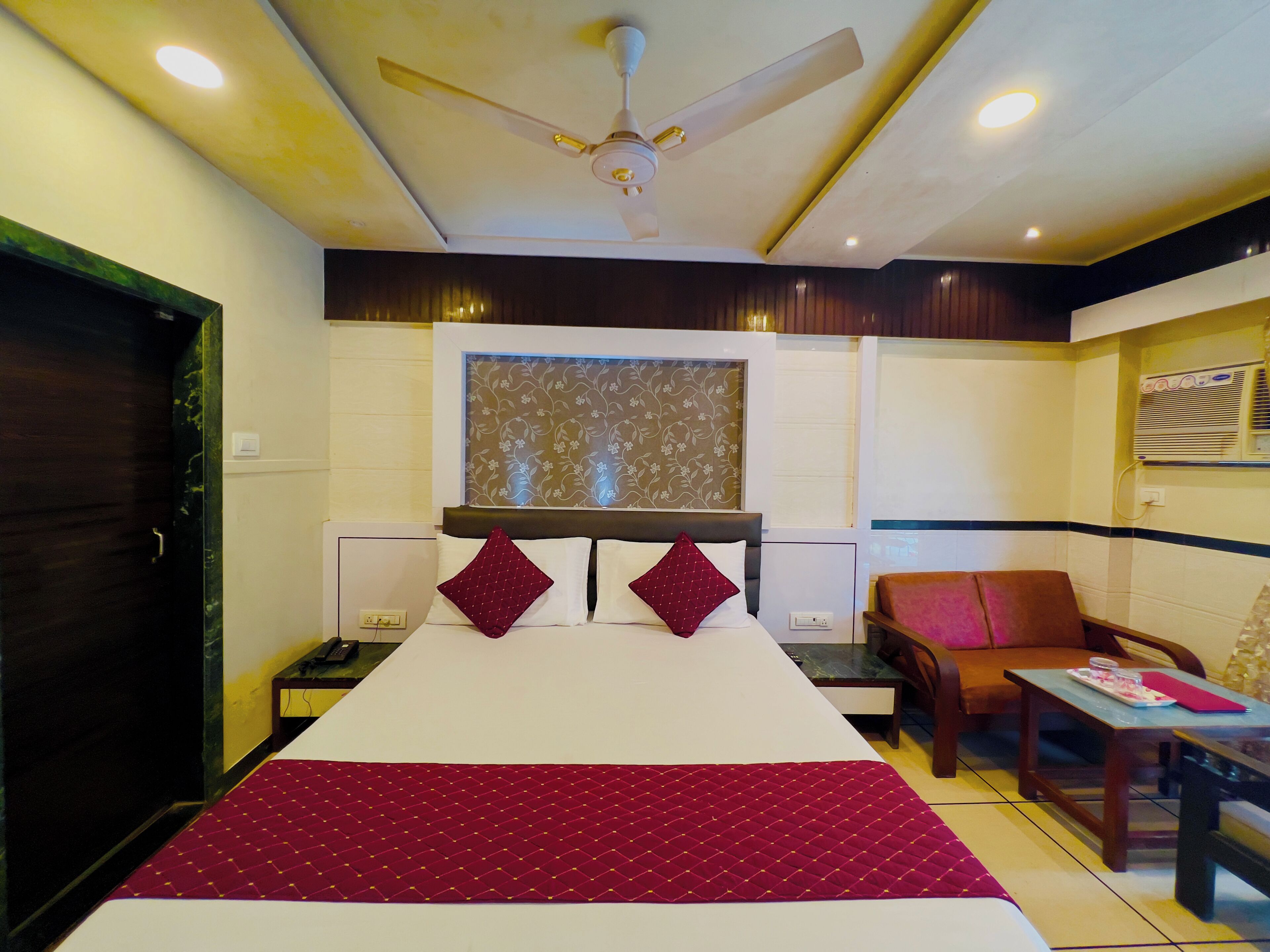 A hotel room with a bed, a desk, a chair, and a ceiling fan.