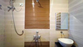 Un baño con lavamanos blanco, ducha y toallero.