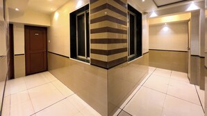 A hotel corridor with a brown door labeled '209', a striped wall, and a shiny tiled floor. - Hotel Dwaraka (Mumbai)