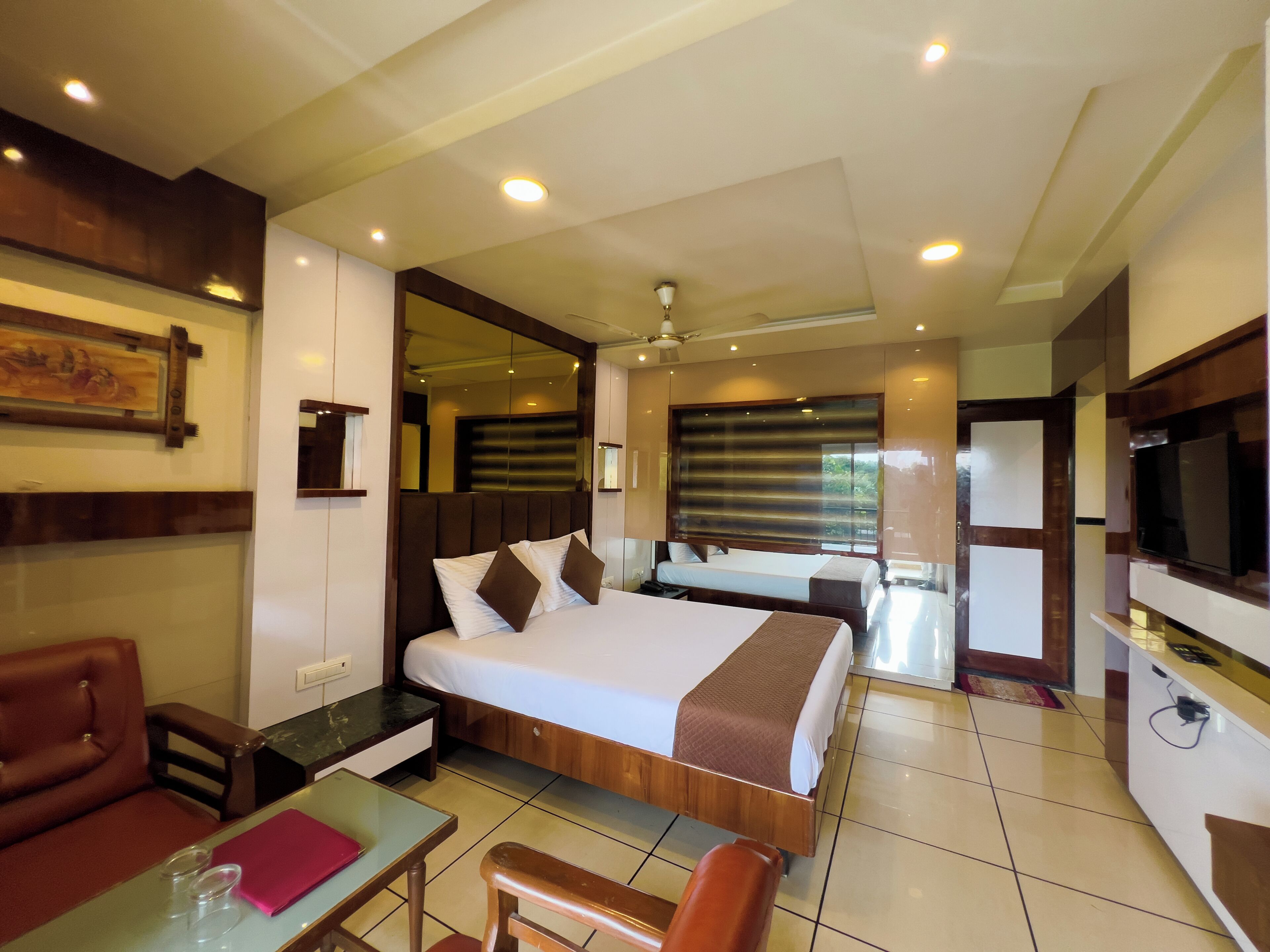 A hotel room with a large bed, a TV, a desk, and a sofa.