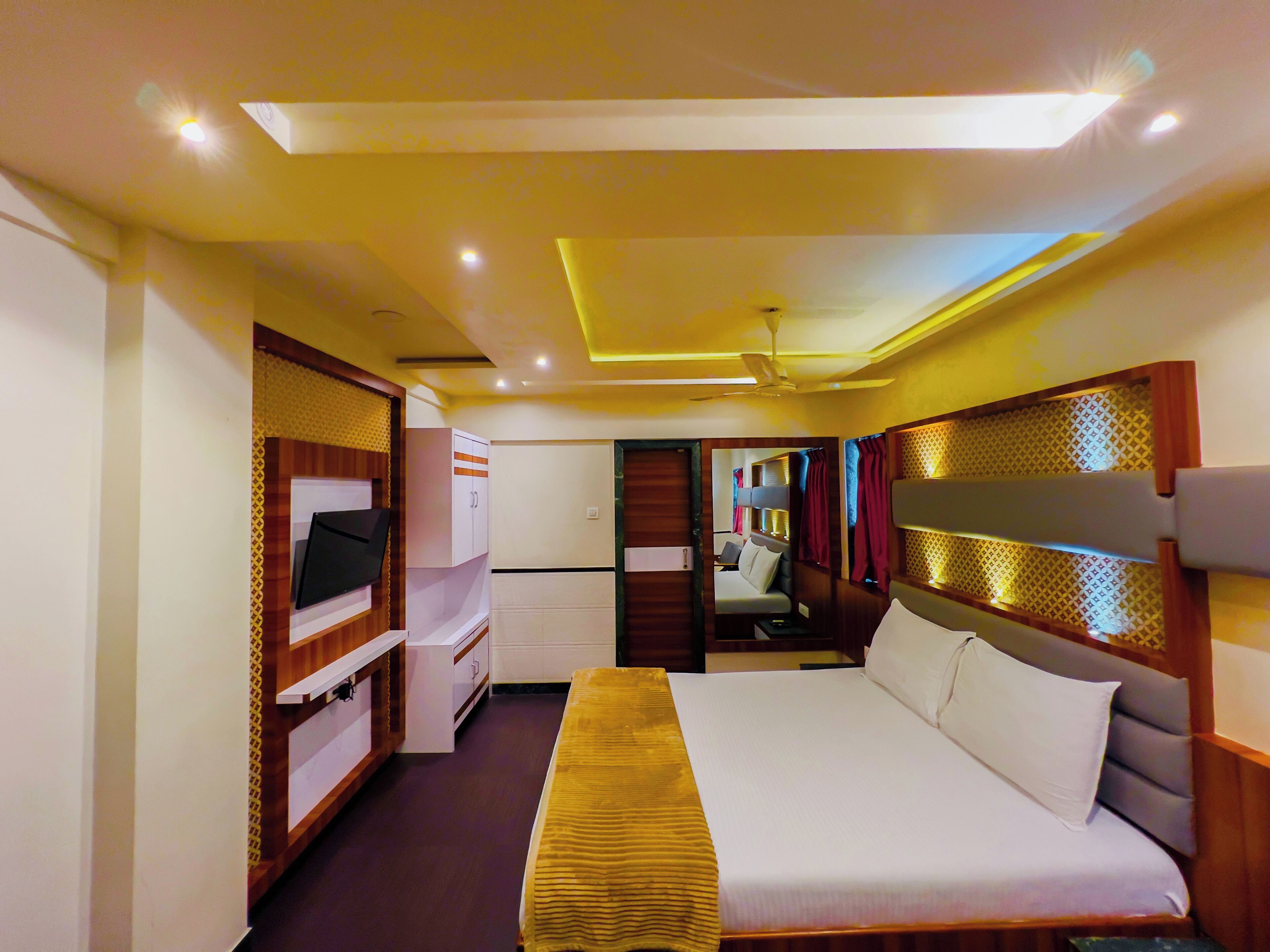 Une chambre d’hôtel avec un lit, une télévision, une armoire et un miroir.