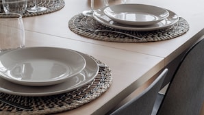 A dining table set with plates, glasses, and a vase of flowers. - Modern 2BR Apartment with Sauna & Large Balcony (Tampere)