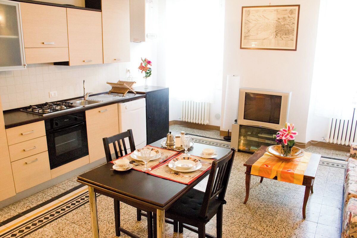 A compact kitchen with a dining area, featuring a stove, oven, and a dining table set with plates and glasses.