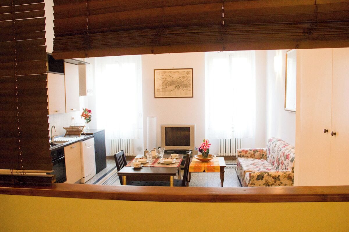 A dining area with a table set for two, a sofa, and a television.