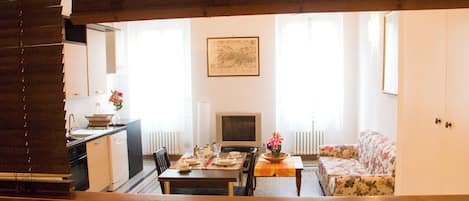 A dining area with a table set for two, a sofa, and a television.