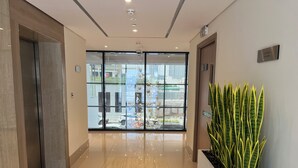 A modern hotel lobby with a glass door entrance, a potted plant, and a sign indicating the first floor.