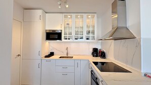 Eine moderne Küche mit weißen Schränken, einer Edelstahl-Mikrowelle, einem Gasherd und einer Kaffeemaschine.
