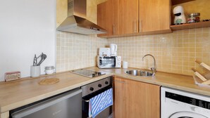 A compact kitchen with a dishwasher, oven, microwave, and sink. - Ideal Apartment in Osséja (Osséja)