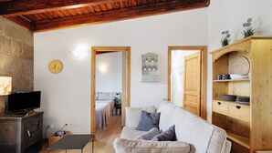 A cozy living room with a sofa, a television, a wooden cabinet, and a fireplace. - Ideal Apartment in Osséja (Osséja)