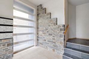 A staircase with stone steps and a wooden handrail, a set of lockers, and a glass door.