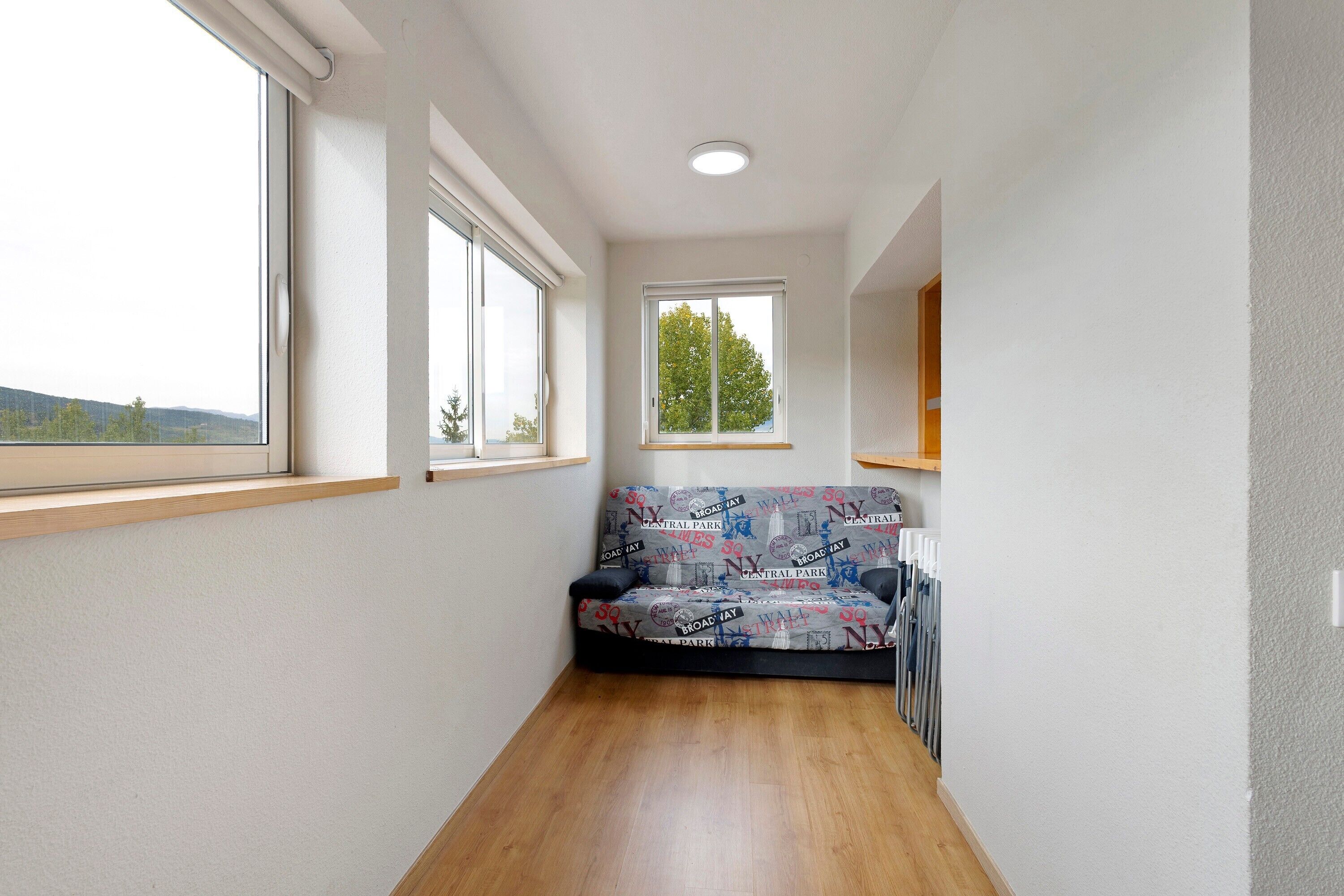 A narrow hallway with a sofa, a window, and a radiator.