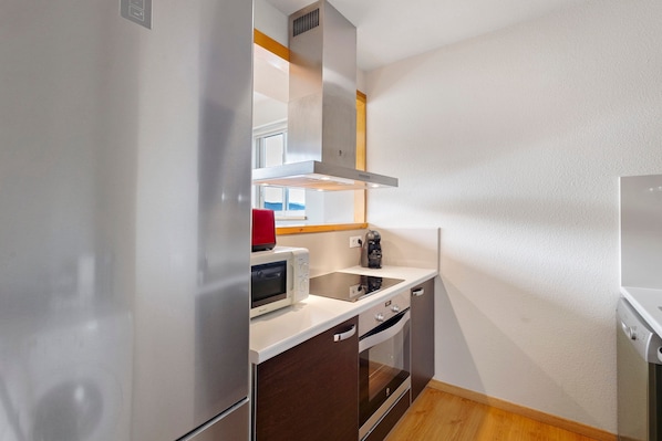 A compact kitchen with a microwave, kettle, and oven.