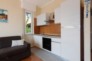 Una cucina compatta con mobili bianchi, forno integrato e tappeto grigio.
