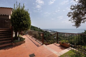 Un sendero pavimentado con barandilla que lleva a un mirador con vistas al mar y al paisaje urbano distante.