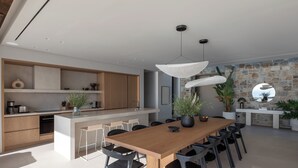 Een moderne keuken met een centraal eiland, zwarte stoelen en hanglampen.