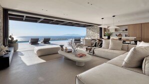 Een moderne woonkamer met een grote bank, een salontafel en uitzicht op zee.