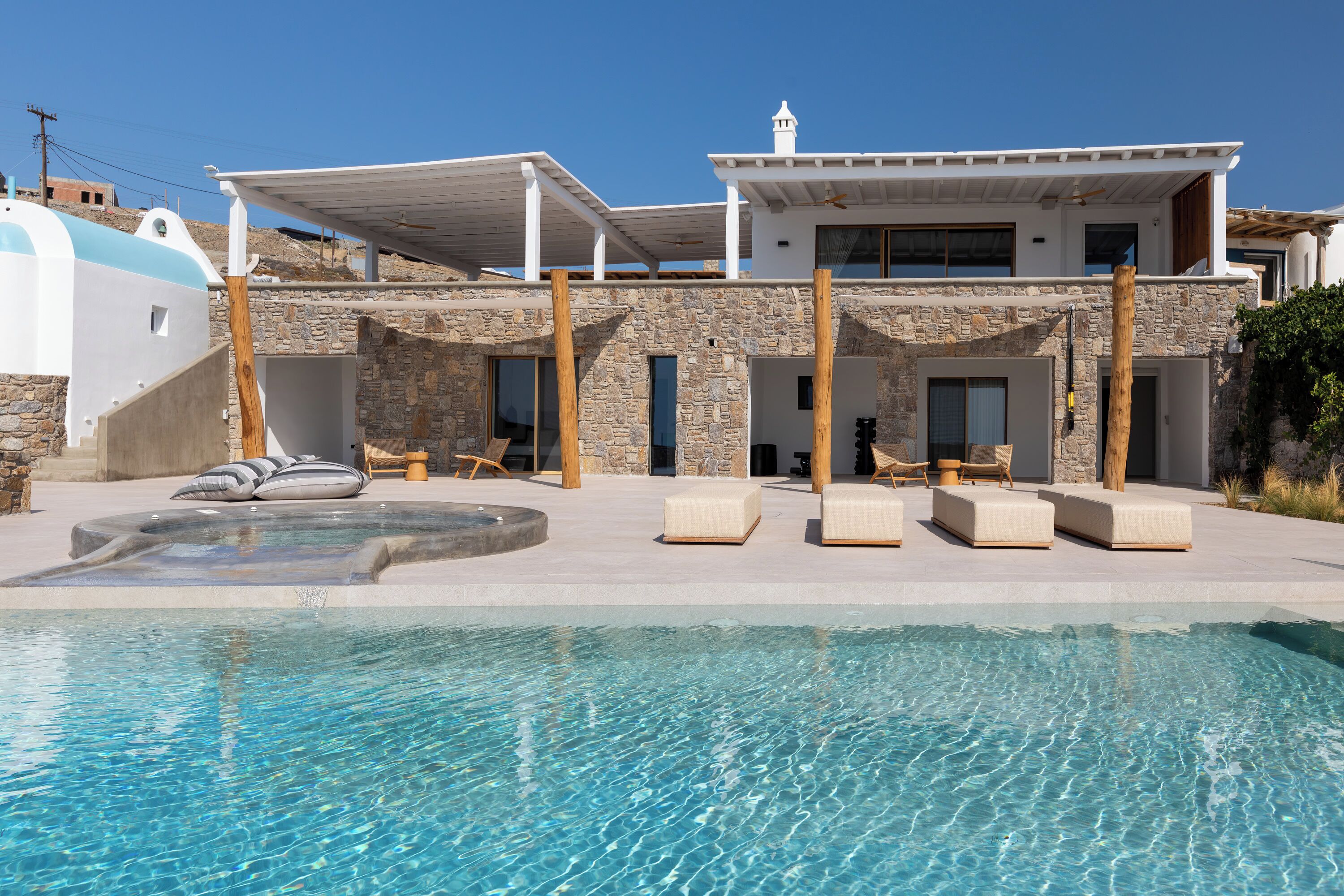 A modern house with a swimming pool, stone walls, and outdoor seating.