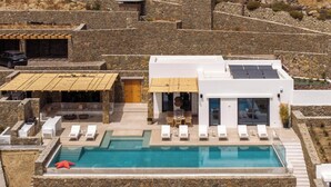 A modern villa with a swimming pool, outdoor seating, and a stone facade.