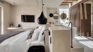 Une chambre moderne avec un grand lit, un bureau intégré, une coiffeuse avec un miroir et une grande fenêtre.