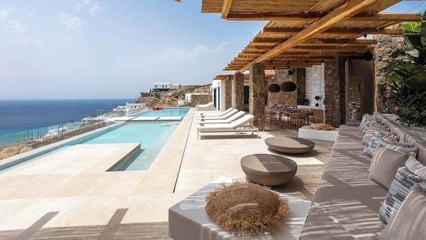 Un espace de détente extérieur luxueux, doté d’une piscine, de sièges confortables et offrant une vue sur l’océan.