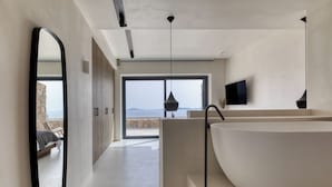 Ein modernes Badezimmer mit einer großen Badewanne, einem Spiegel und Blick ins Freie.