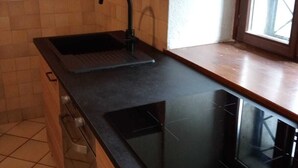 Een keuken met een zwart aanrecht, een gootsteen en een raam.